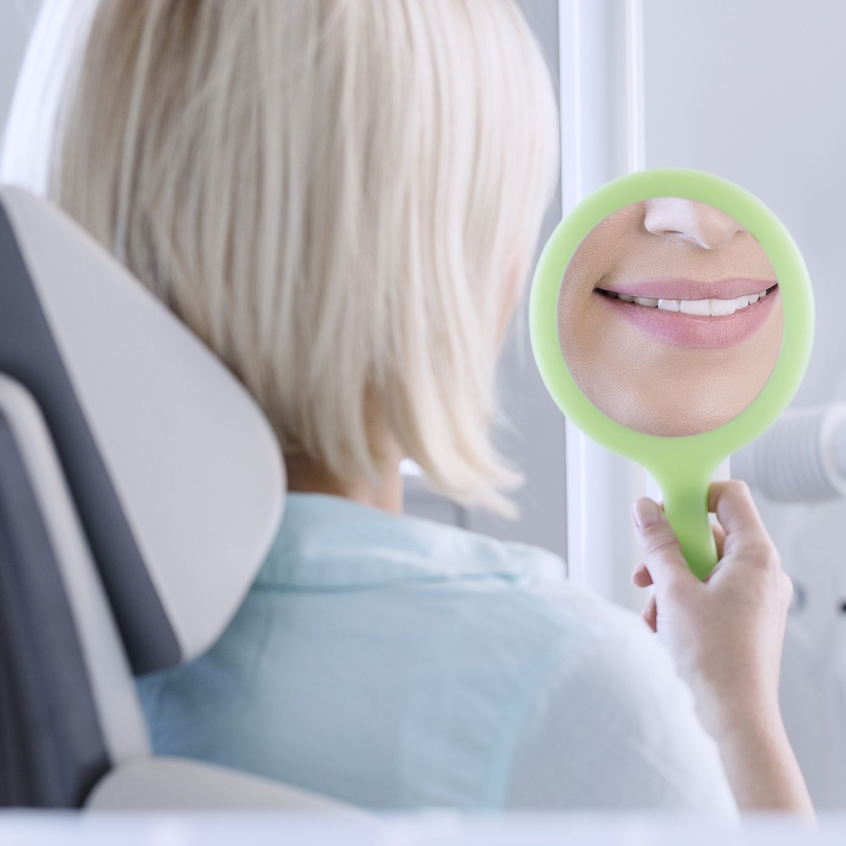 Woman smiling into handheld mirror